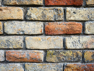 Close-up of an old brick wall in yellow and red tones with lots of texture.