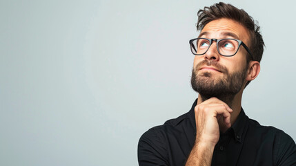 Obraz premium A man in glasses ponders deeply while looking upward, contemplating his next move