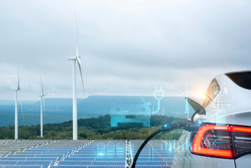 Electric vehicle charging near solar panels and wind turbines, symbolizing renewable energy...