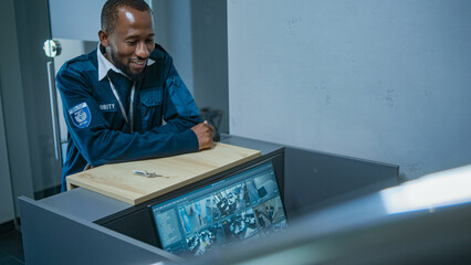 Caucasian female safeguard sits at workplace in office, works using computer. PC monitor with CCTV cameras video footage. African American security guard gives keys to colleague. Surveillance system.