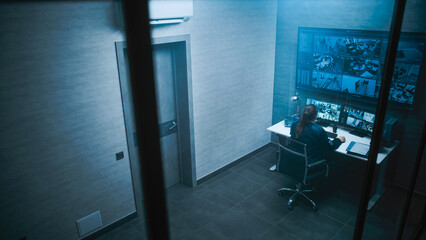 Female CCTV operator controls security cameras in monitoring center on computer. Surveillance video footage displayed on multiple monitors and big digital screen.