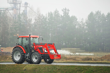 Obraz premium Tractor on foggy road in rural farming area