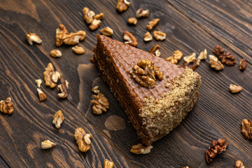A piece of cake with walnuts on a dark wooden background.