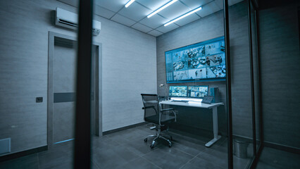 View on the workplace for surveillance operator or dispatch in dark modern monitoring room. CCTV...