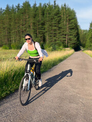 Obraz premium Woman riding bicycle along peaceful countryside road