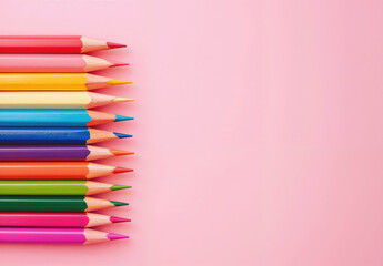 Row of colorful pencils on a pink background with copy space for text