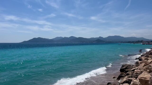 View of the Bay of Cannes with red rocks of Cap Esterel, Cannes, Cte d Azur, France. Cannes beach - France, Provence-Alpes-Cote d'Azur, View from beach to yachts in the evening. View of sea