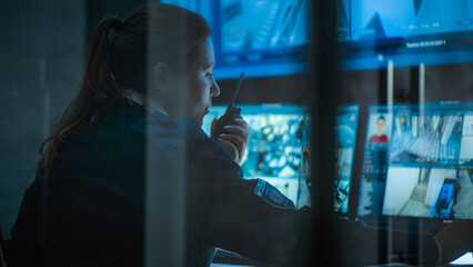 Close up of female CCTV operator working on computer in monitoring center with security cameras,...