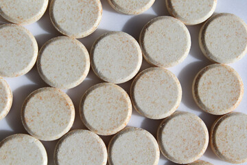 Round Vitamin C tablets supplements arranged closely together on a white background