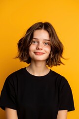 Fototapeta premium Portrait Of A Young Woman Standing Against A Yellow Background, Looking Happy