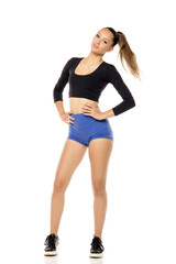 Sporty fit woman in blue shorts and black shirt isolated on white studio background. Full body of slim attractive female with flat belly