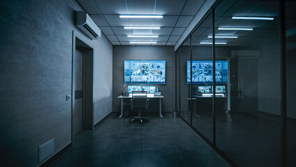 Workplace for security worker or operator in dark modern monitoring center. Computer monitors, tablet display and big digital screen showing surveillance video footage from the CCTV cameras in office.