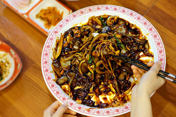 식탁 위에 쟁반짜장을 젓가락으로 먹는 모습
