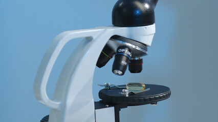 Close-up of a fish oil, omega 3 or omega 9 pill placed on a microscope sample stand. Scientific research on medicinal products, photos for product advertising
