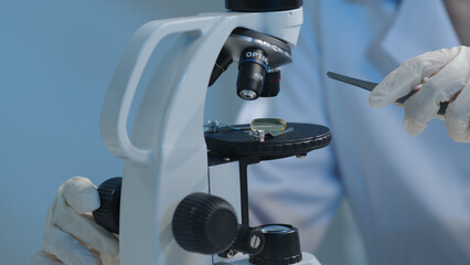 The scientist used tweezers to place a fish oil pill on the microscope's specimen tray and prepare for research. Research scientific products, medicinal products, fish oil, omega or vitamins