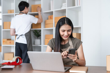 Young Couple Packing Merchandise and Managing Online Sales Together in a Modern Home Office Setting