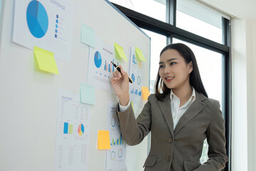 Young Accountant Presenting Financial Graphs and Data Analysis on Whiteboard in Modern Office Setting