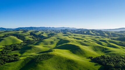 Obraz premium Sun-kissed green hills stretch towards a cloudy sky, painting a breathtaking panorama of nature's beauty