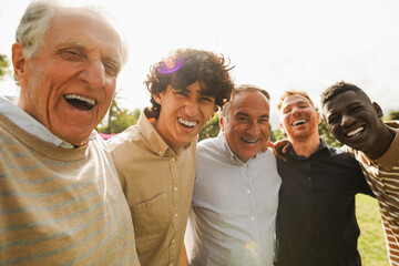 Multi generational men smiling in front of camera - Male multiracial group having fun togheter outdoor - Focus on left boy face