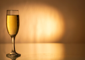 A champagne flute filled with cold champagne, placed on the left side of a gold gradient background, evoking the spirit of festive celebrations.