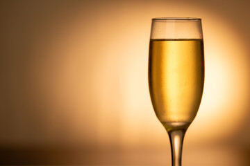 A close-up of a champagne glass brimming with champagne, set to the right on a golden gradient background. Ideal for Christmas and New Year's celebrations.