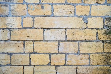 A brick wall with a white and yellow color. The wall is made of bricks and has a rough texture