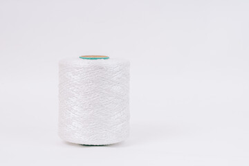 A spool of white braided fiberglass thread with a green core, isolated on a white background. Industrial material concept with copy space.
