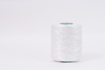 A spool of white braided fiberglass thread with a green core, isolated on a white background. Industrial material concept with copy space.