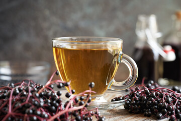 A cup of tea with black elderberry syrup, on a table