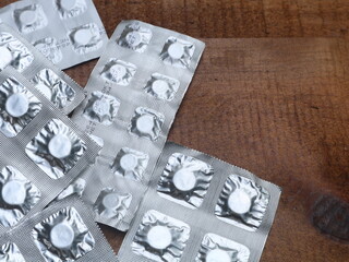 Tablet medicine is packaged in aluminum foil packaging on a wooden board background