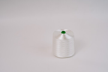A spool of white fiberglass thread with a green top, displayed against a plain white background, showcasing the texture and weave of the material...