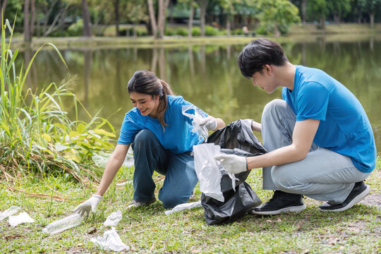 Young Volunteer Couple Collecting Trash in a Park to Promote Environmental Conservation and Community Cleanliness