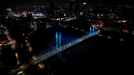 Naklejka premium Mandela Bridge At Johannesburg In Gauteng South Africa. Night Scape Town. Illuminated Cable Stayed Bridge. Johannesburg At Gauteng South Africa. Landmark Bridge. Colorful Skyline.