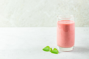 Healthy protein strawberry smoothie, yogurt milkshake in glass with mint leaves.