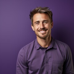 Obraz premium A cheerful man wearing a purple shirt stands against a matching purple background, smiling at the camera great for using in casual professional settings, lifestyle blogs, or personal branding content