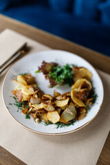 delicious dish with crispy potatoes, roasted mushrooms, fresh vegetables, and fragrant herbs on a beautiful white plate in a cozy, charming restaurant