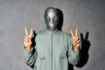 Mystery man with duct tape face showing hand gesture V sign for victory or peace