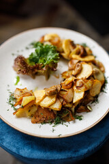 delicious dish with crispy potatoes, roasted mushrooms, fresh vegetables, and fragrant herbs on a beautiful white plate in a cozy, charming restaurant