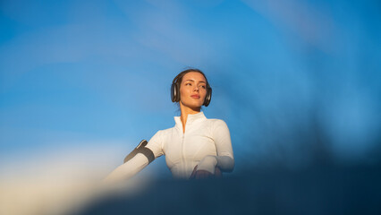 nice sporty young girl with big headphones sitting in lotus position on roof of city office building
