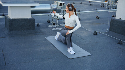 Sporty girl in big headphones doing muscle stretching