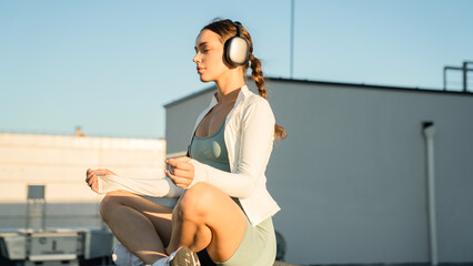 A woman is sitting on the roof, meditating and enjoying the sunshine. Concept of peace and relaxation, as the woman is focused on her breathing and the natural surroundings