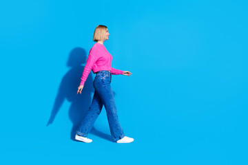 Full body profile portrait of nice young woman walk empty space wear sweater isolated on blue color background © deagreez