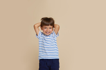 Front portrait of a little boy being very happy, isolated over beige background. Copy space.