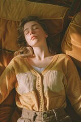 Obraz premium A serene, young woman in a comfortable indoor or outdoor setting, peacefully sleeping with closed eyes. She is wearing casual clothing and is relaxed on a lounge chair bathed in sunlight.