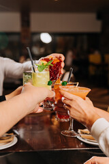 Group of friends toasting with cocktails in a vibrant bar setting, celebrating togetherness