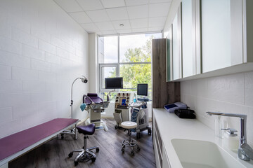 Interior of hospital room with gynecologist's chair and ultrasound machine in a gynecologist clinic.
