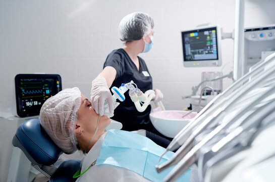 Doctor making anesthesia while female patient lying in dentist chair