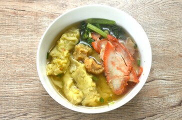 Chinese dumpling topping slice red barbecue pork and cabbage in clear soup on bowl