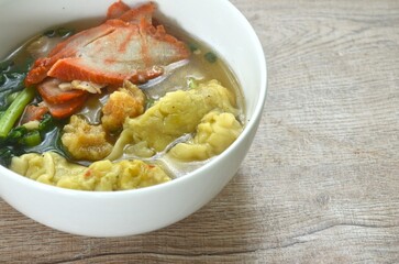 Chinese dumpling topping slice red barbecue pork and cabbage in clear soup on bowl