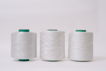 Three spools of white fiberglass thread are displayed side by side, showcasing different textures and sizes against a plain background.